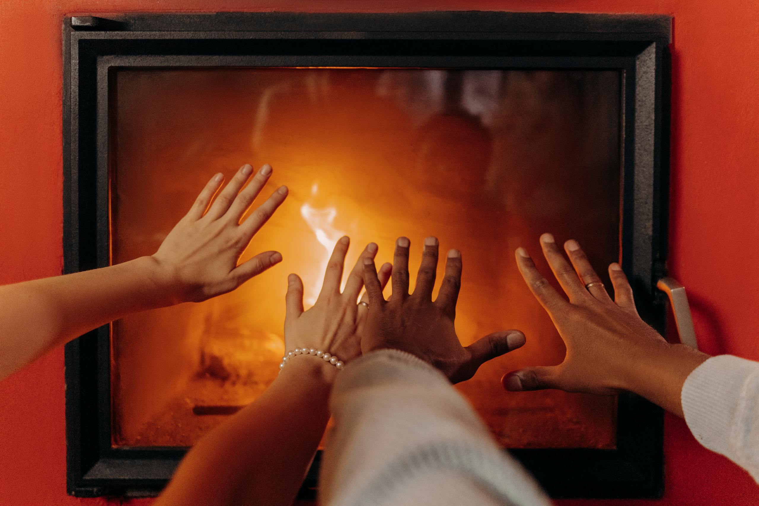 Close-up of hands warming by a cozy fireplace, radiating warmth and comfort.